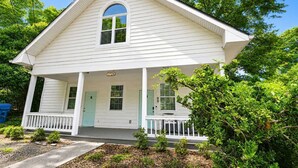 A white single-story house with a porch, a small front yard, and a mailbox. - West Midtown | Hot Tub • Fire Pit • Parking (Atlanta)