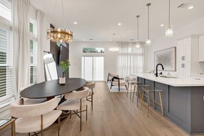 A modern kitchen with a central island, pendant lighting, and a dining area with a round table and chairs. - Wonderful 3-bedroom house with AC in vibrant  Houston — Minutes from Everything (Houston)
