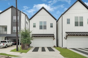 A row of two-story houses with attached garages, a driveway, and a small tree. - Wonderful 3-bedroom house with AC in vibrant  Houston — Minutes from Everything (Houston)