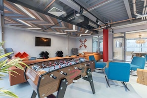 Ein moderner Innenraum mit Kicker, Sofas und einem an der Wand montierten Fernseher.