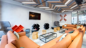 A modern living room with orange sofas, a coffee table, and a TV mounted on the wall. - Student Only Livin (Cardiff)