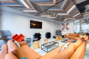Ein modernes Wohnzimmer mit orangefarbenen Sofas, einem Couchtisch und einem an der Wand montierten Fernseher.