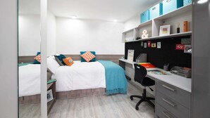 A bedroom with two beds, a desk, and a shelving unit with storage boxes. - Student Only Livin (Cardiff)