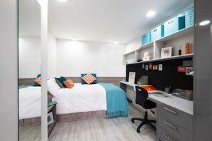 Ein Schlafzimmer mit zwei Betten, einem Schreibtisch und einem Regal mit Aufbewahrungsboxen.
