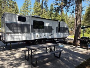 Un camper fermo chiamato 'SALEM' con un tavolo da picnic davanti.