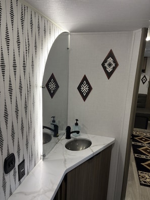 Un bagno con lavandino, specchio, parete decorata e pannelli murali ornamentali.
