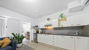 A modern kitchen with white cabinetry, a built-in microwave, and a stainless steel sink. - 1 Brm, Air Con, Parking, Wifi, Walk to City (Kangaroo Point)