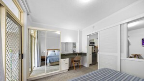 A bedroom with a bed, a desk, a kitchenette, and a wardrobe. - 1 Brm, Air Con, Parking, Wifi, Walk to City (Kangaroo Point)