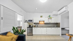 A modern kitchen with white cabinets, a built-in microwave, and a stainless steel refrigerator. - 1 Brm, Air Con, Parking, Wifi, Walk to City (Kangaroo Point)
