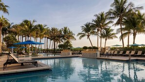 A swimming pool with lounge chairs and umbrellas, surrounded by palm trees. - Thanksgiving in Florida! 2 Bedroom Ocean View Villa - Marriott's Oceana Palms (Riviera Beach)