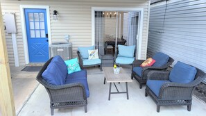 A covered patio area with wicker furniture, a blue door, and a grey utility box.