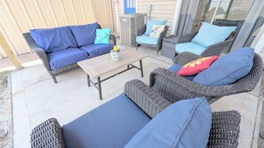 An outdoor patio with wicker furniture, including a sofa and chairs, a wooden table, and a decorative vase. - Sleep 6•Pet Friendly•Fully Stocked East Bernard (East Bernard)