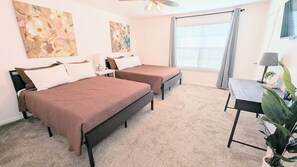 Une chambre avec deux lits, un bureau et une fenêtre avec des stores.