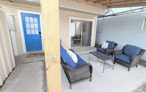 A covered patio with wicker furniture, a blue door, and a sliding glass door leading to an interior space. - Sleep 6•Pet Friendly•Fully Stocked in East Bernard (East Bernard)