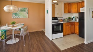 Eine moderne Küche mit Holzausstattung, einem schwarzen Kühlschrank und einem Essbereich mit rundem Tisch und Stühlen.