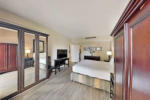 Ein Hotelzimmer mit Bett, Schreibtisch, Fernseher, Kleiderschrank und Spiegel.