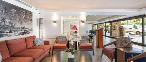 A modern hotel lobby with a sofa, chairs, a coffee table, and a large window.