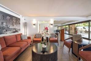 Eine moderne Hotelhalle mit einer Couch, Sesseln, einem Couchtisch und einem großen Fenster.