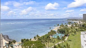 A coastal view with a beach, palm trees, and a clear sky. - Oceanfront Paradise 1Bdrm at the Waikiki Shore (Honolulu)
