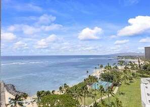 Küstensicht mit Strand, Palmen und blauem Himmel.