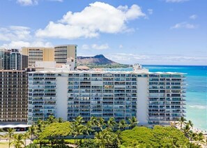 Ein Hochhaus-Hotel mit zahlreichen Stockwerken, Blick auf den Strand und einem Berg im Hintergrund.