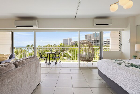 Una habitación de hotel moderna con balcón, un sofá, una cama y un área de comedor.