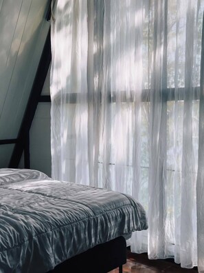 A room with a bed, a window with sheer curtains, and a sloped ceiling. - Private cozy riverside vacation house (Pong Sawai 15)