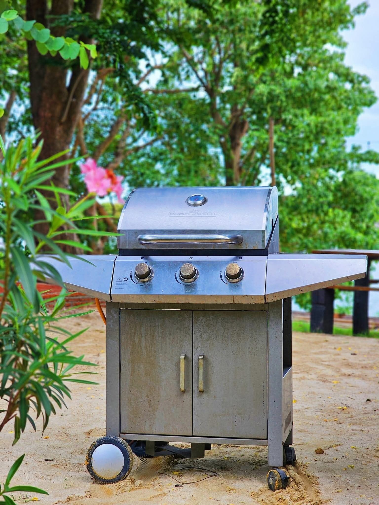 Een draagbare barbecue met bedieningspaneel, wielen en een opbergvak.