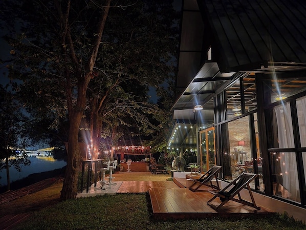 A modern outdoor area with a wooden deck, lounge chairs, and a view of a body of water.