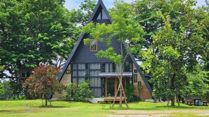 Ein modernes Haus mit einem dreieckigen Dach, umgeben von üppigem Grün und einer Picknickgegend.