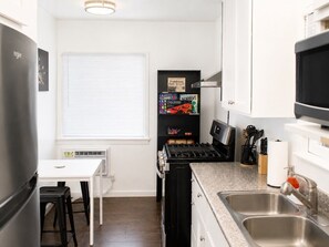 Cocina compacta con estufa, lavamanos y un pequeño comedor.
