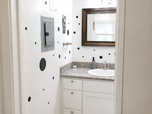 Un baño con lavamanos blanco, un espejo y un perchero para toallas.