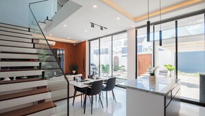 Una cocina moderna con zona de comedor de cristal, una escalera y vistas al exterior.