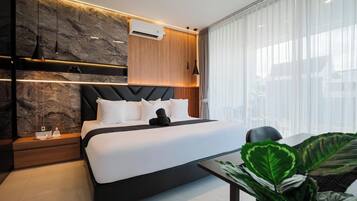 Une chambre moderne comprenant un lit, des tables de chevet, un appareil de climatisation et une grande fenêtre avec des rideaux.