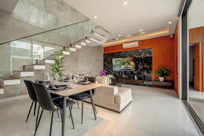 Un interior moderno con comedor, sofá, escalera y cocina.