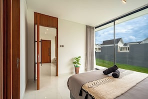 Un dormitorio moderno con una cama grande, una planta en maceta y vistas a una zona residencial.