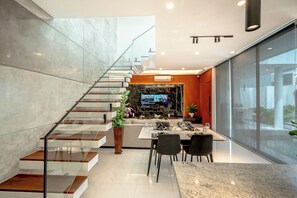 A modern interior with a staircase, a dining area, and a living space with a TV. - Sky Beach Villa by Betterplace (Canggu)