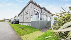Una moderna casa a due piani con un giardino anteriore, un vialetto e un'auto parcheggiata davanti.