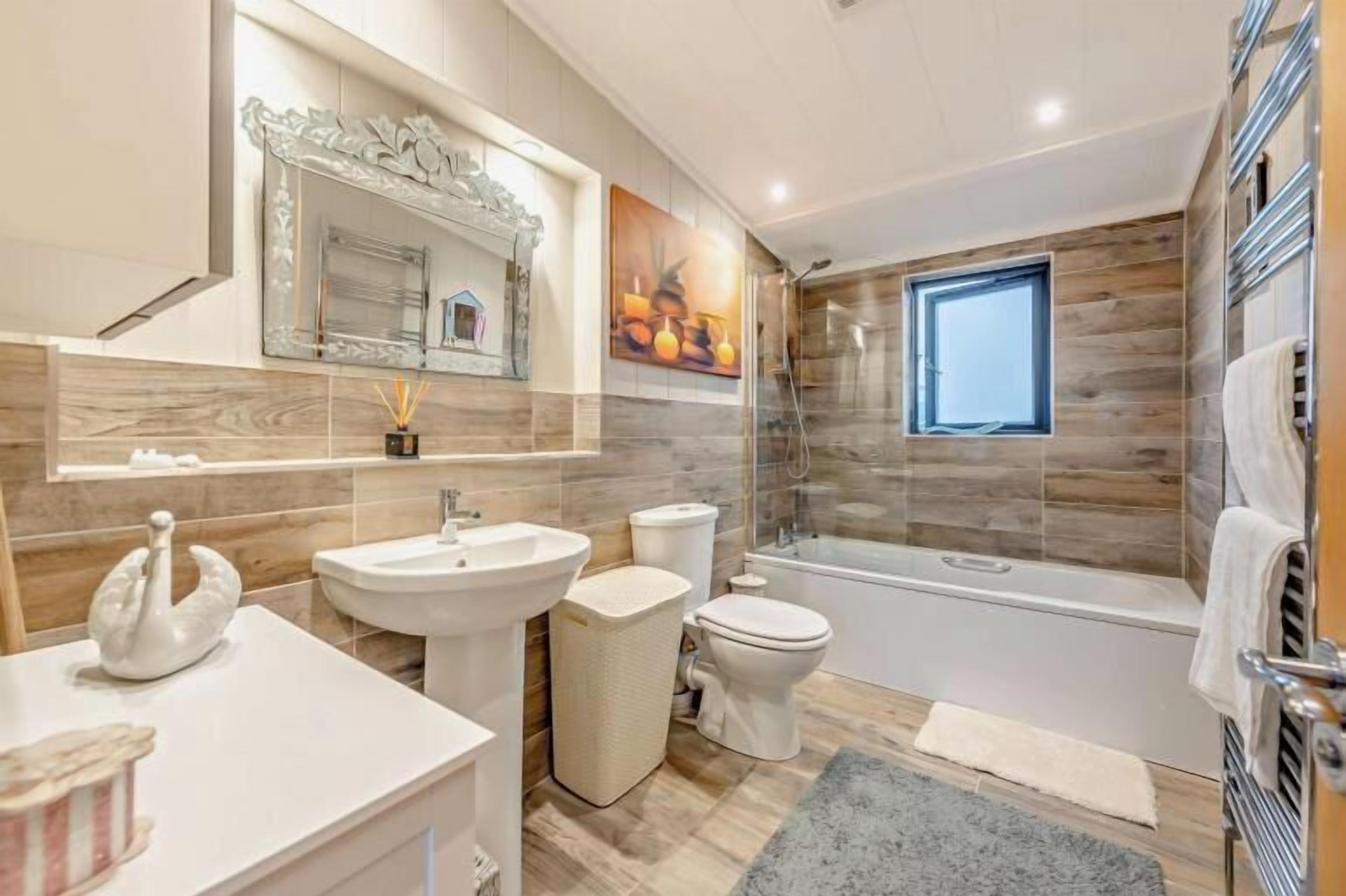 Une salle de bain moderne dotée d’une grande baignoire, de toilettes séparées et d’un meuble-lavabo avec un miroir.
