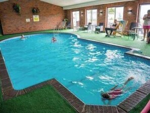 Ein Hallenbad mit Backsteinwand, künstlichem Rasen und Liegestühlen.