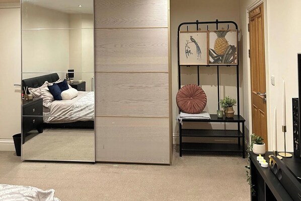 Un dormitorio con cama, mesita de noche y espejo.