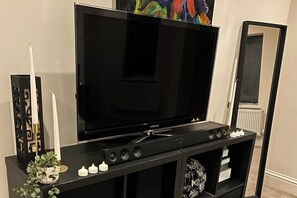 Un mueble multimedia negro con un televisor de pantalla plana, un candelabro decorativo y una planta pequeña.
