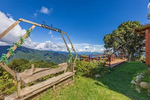 A wooden sign with 'Jaulaires' written on it, a wooden bench, a red wooden structure with a roof, and a view of mountains. - Jaulares Country House (Rivas)