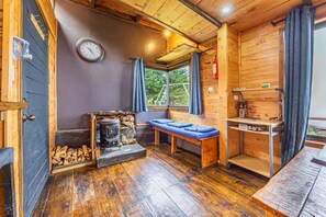 A cozy cabin with a stone fireplace, a bench, and a wooden table. - Jaulares Country House (Rivas)