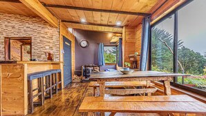 A rustic wooden interior with a large dining table, benches, a brick wall, and a view through large windows. - Jaulares Country House (Rivas)