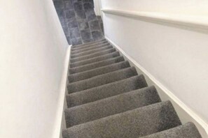 A staircase with carpeted steps and white walls. - 4 bed 4 shower room Sleeps 7 Free Parking Long Term stays (Corby)