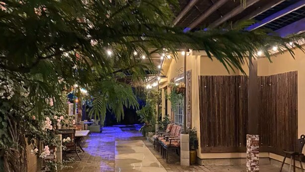 Un patio al aire libre con un sendero de ladrillo, mobiliario y plantas en macetas.