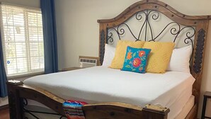 Una cama bien hecha con cabecera de madera y un cojín decorativo.