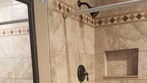 Un baño con lavamanos, espejo, ducha y paredes de azulejos.