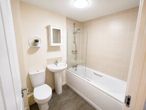 A bathroom with a toilet, sink, and bathtub. - House Sleeps 7 with Enclosed Garden (Salford)
